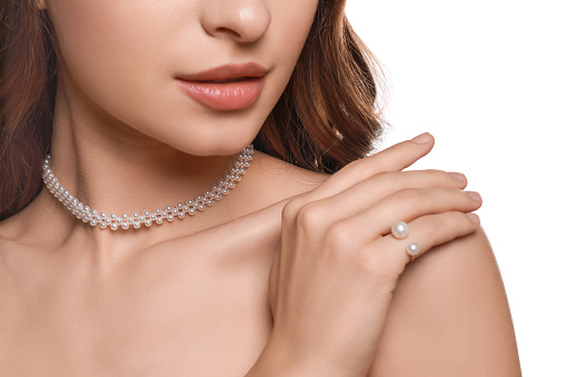 The bride wearing a diamond ring touches the pearl necklace on her neck