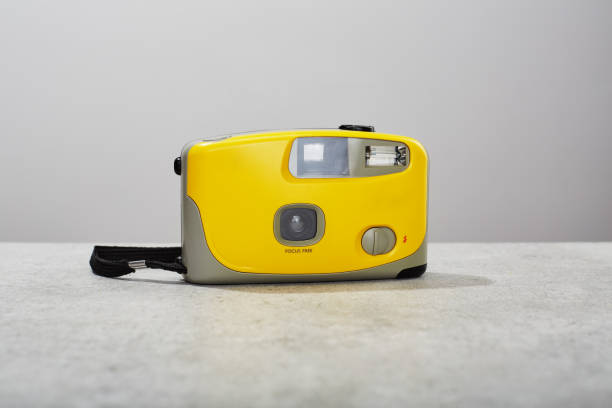 istock Yellow colored 35mm point and shoot film camera on concrete background 1488831633