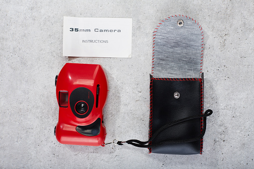 Red colored 35mm point and shoot film camera with instructions booklet and leather carry case
