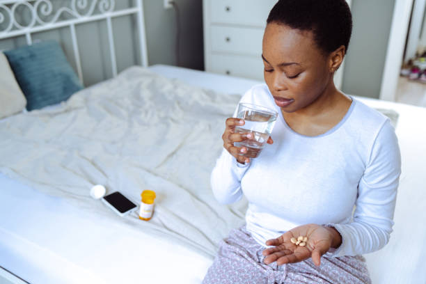 istock Uncertain young woman taking medicines in bed 1488836695