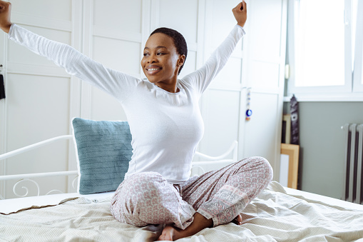 Young woman waking up and stretching in bed