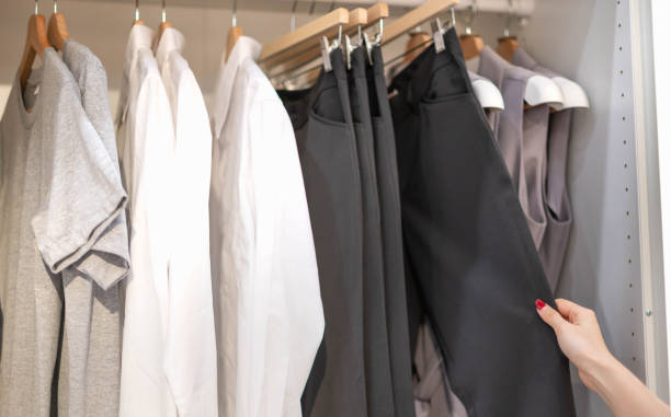 istock Female hand choosing clothes for checked pattern trouser on the rack in cloth shop at a department store. Check price, discount, and promotion of clothing products. 1488841020