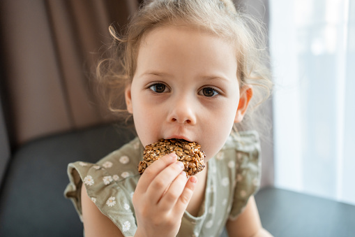 Close-up view of piece of cookies with banana and seeds in little girl hand. High quality photo