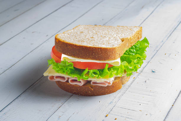 istock Sandwich with Ham, cheese, lettuce, and tomatoes inside of a loaf bread 1488843231