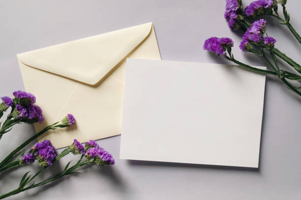 istock White blank greeting or invitation card and envelope with white flowers decoration on gray background. 1488845437