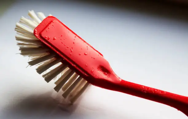 Umea, Norrland Sweden - June 10, 2019: a used red dish brush in the kitchen window