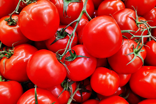 Close-up on a stack of round tomatoes in bunched on a market stall.