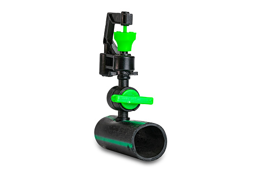 Small black and green color plasticwater sprinkler mounted on old dirty p.e.tube isolated on white background with clipping path.
