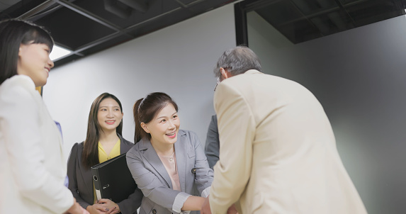 asian businessman and business woman are greeting with company senior client in hallway