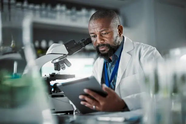 Photo of Black man thinking, science and tablet for online research, laboratory and healthcare sample. African American male, scientist or research in lab, digital data and update experiment results and focus