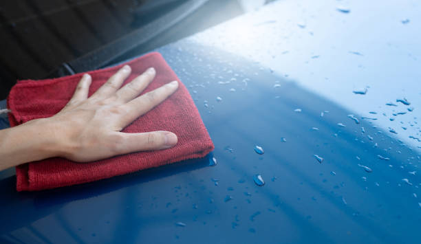 Car wash service. Man hand holding red microfiber cloth polish blue car and water drop after cleaning. Auto care service business concept. Man cleaning and detailing luxury car with microfiber cloth. servicio de lavado de autos. mano del hombre sosteniendo tela de microfibra roja pulido azul coche y gota de agua después de la limpieza. concepto de negocio de servicio de cuidado automático. hombre limpiando y detallando coche de lujo con tela de micro