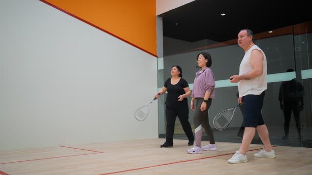 Active senior couple learning playing squash