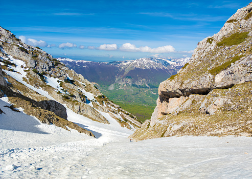 Monte Amaro, Italy - 6 May 2023 - The snow mountain summit in the Majella mount range, Abruzzo region, with alpinistic way named Rava del Ferro. Here a view of canal view with alpinist.