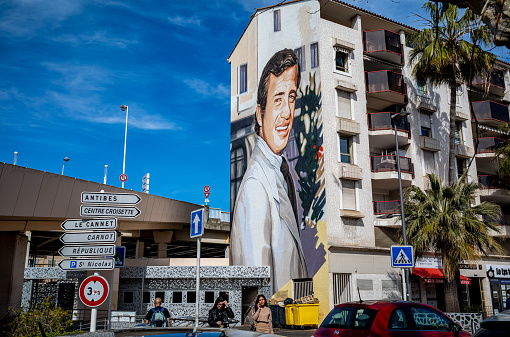 A tall building in Cannes, France with a large painted portrait of a man on the side.  This building is along one of the main roadways that goes through Cannes on the French Riviera.