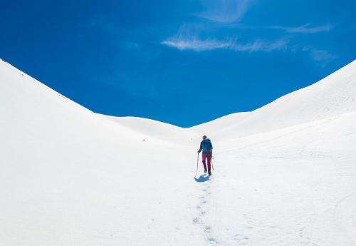 Monte Amaro, Italy - 6 May 2023 - The snow mountain summit in the Majella mount range, Abruzzo region, with alpinistic way named Rava del Ferro. Here a landscape view with girl alpinist.