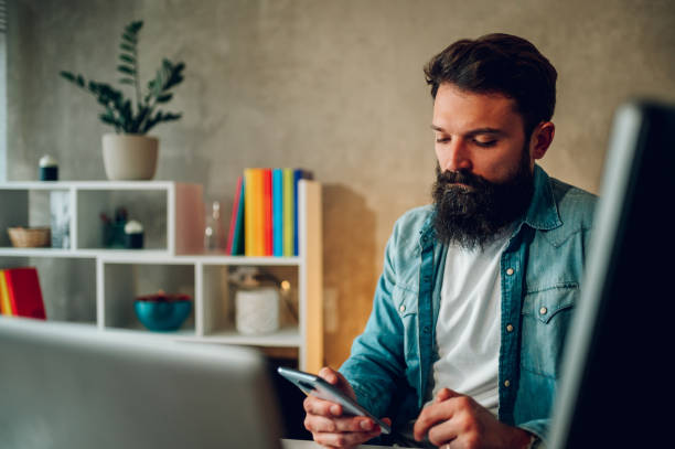 istock A senior developer is sitting at his cozy home office in the evening and testing the mobile app on his phone. 1488868924