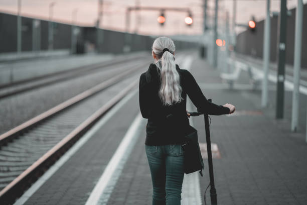 istock Rear view of woman with e-scooter walking alone at rail platform 1488869326