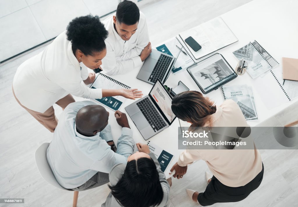 Business people, laptop and meeting in planning above for web design, strategy or brainstorming at the office. Top view of group designers working on computer for team project plan or idea on table Teamwork Stock Photo