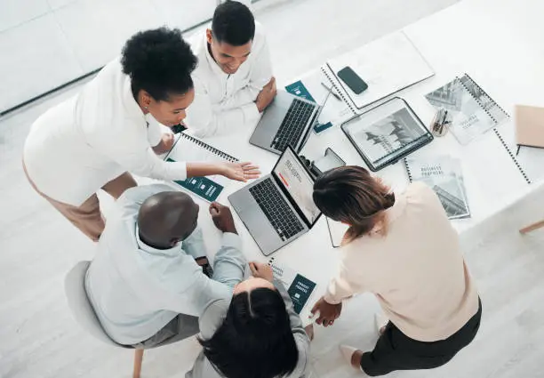 Photo of Business people, laptop and meeting in planning above for web design, strategy or brainstorming at the office. Top view of group designers working on computer for team project plan or idea on table