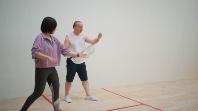 Active senior couple learning playing squash