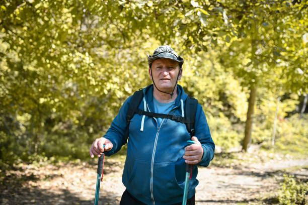 randonneur âgé souriant s’arrêtant dans un pré - pointer stick audio photos et images de collection