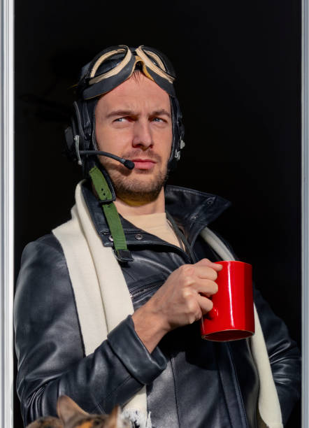 Portrait of young man in leather jacket, white scarf, leather helmet, glasses and flight headset