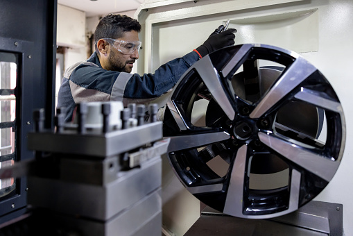 Latin American mechanic testing an alloy wheel at a car garage - automobile industry concepts