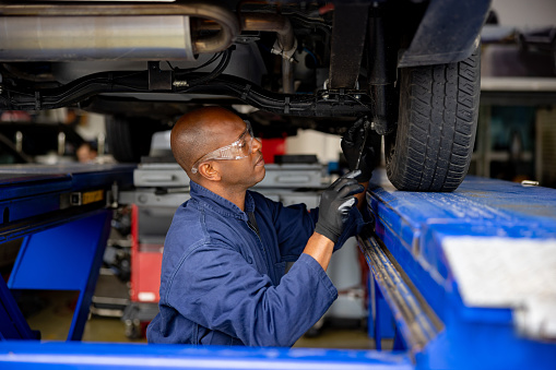 African American mechanic fixing the suspension on a car at the auto repair shop
