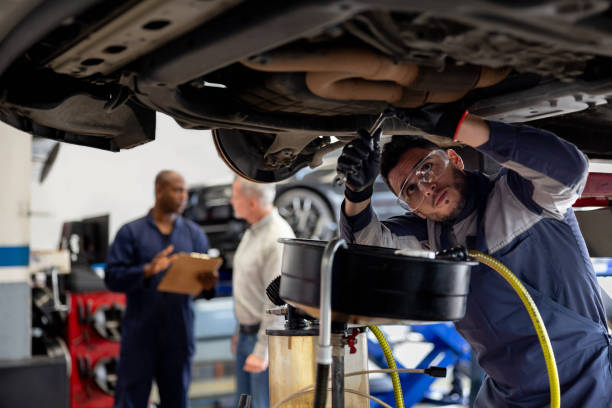 Mechanic working at an auto repair shop fixing a car Latin American mechanic working at an auto repair shop fixing a car - vehicle breakdown concepts mechanic working under car stock pictures, royalty-free photos & images