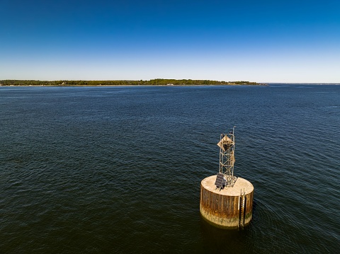 An aerial view of a circular concrete base with a solar-powered beacon and antenna in the middle of the waters of Oyster Bay on Long Island, NY