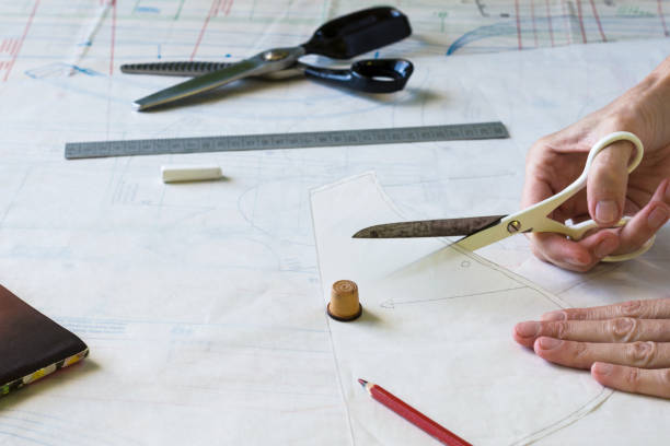 istock Seamstress is cutting drawing for a dress with scissors. Style and design development and creating garment, clothes sew and repair service 1488882145
