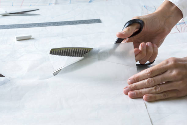 istock Seamstress is cutting drawing for a dress with scissors. Style and design development and creating garment, clothes sew and repair service 1488882146