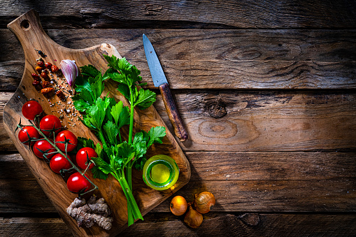 Cutting board with fresh vegetables and spices ingredients shot from above on rustic wooden table. The composition includes onion, ginger, peppercorns, tomato, garlic, celery and extra virgin olive oil bottle. The composition is at the left of an horizontal frame leaving useful copy space for text and/or logo at the right.
High resolution 42Mp studio digital capture taken with SONY A7rII and Zeiss Batis 40mm F2.0 CF lens