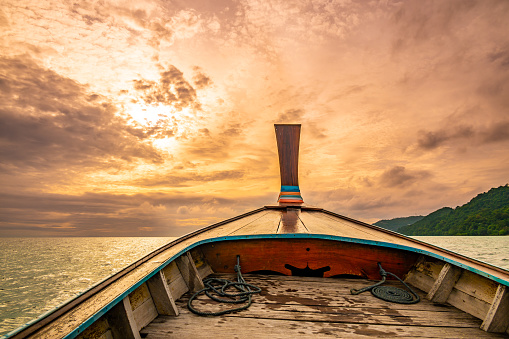 View from long tail boat heading to the dramatic sunset above ocean. Concept of exotic vacation in tropical paradise. Photo taken at Thailand near Ko Phi Phi islands.
