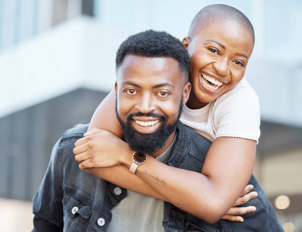 Portrait of black couple piggyback in city for love, care and happiness on date together in Nigeria. Happy man carrying young woman in urban street for outdoor fun, freedom and relax with face smile retrato de una pareja negra a cuestas en la ciudad por amor, cuidado y felicidad en una cita junta en nigeria. hombre feliz que lleva a una mujer joven en la calle urbana para divertirse al aire libre, libertad y relajarse con una sonrisa facial