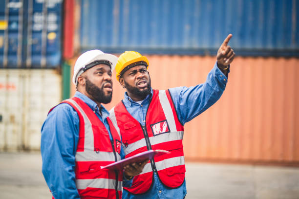 istock Portrait of Two African Engineer or foreman wears PPE checking container storage with cargo container background at sunset. Logistics global import or export shipping industrial concept. 1488890700
