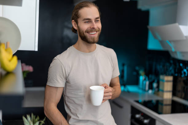 istock Man enjoying morning coffee in kitchen with modern interior, drinking fresh warm beverage at home. 1488891259