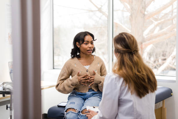 Young adult female patient gestures while explaining her mental health struggles with the doctor stock photo