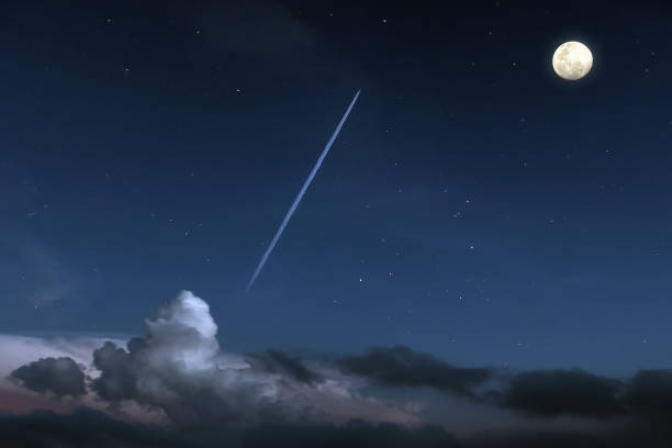 Jet plane with contrail flying through clouds in the night sky with full moon glowing and starry A private jet plane with contrail flying through clouds in the night sky with full moon glowing and starry in the space contrail moon on a night sky stock pictures, royalty-free photos & images