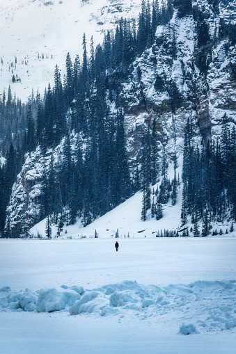 A traveler man walking on frozen lake and snowy mountain in winter at national park