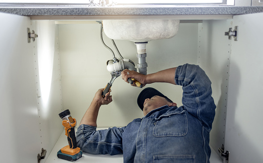 Plumber, man and handyman with plumbing, home renovation and manual labour with tools. Construction, DIY skills and professional, fixing pipe in industry and male with trade, repairs and maintenance