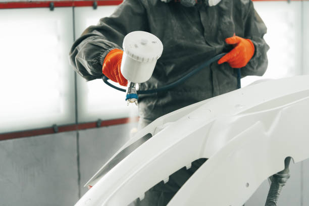 Male painter in respiratory mask and protective suit painting car with spray gun in car service Male painter in respiratory mask and protective suit painting car with spray gun in car service close up colouring stock pictures, royalty-free photos & images
