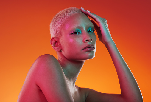 Cosmetics, neon beauty and portrait of woman with makeup and light in creative advertising on orange background. Art, product placement and model isolated in skincare and futuristic mockup in studio.