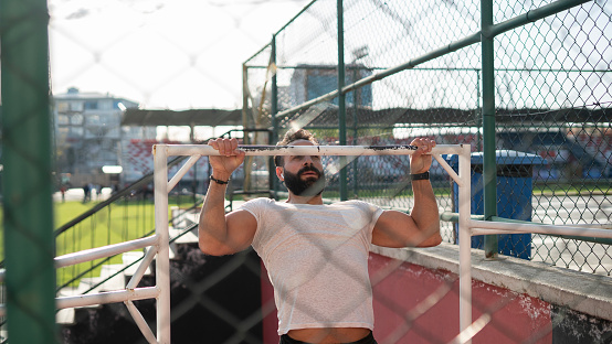 Adult athlete man doing pull-ups in the park