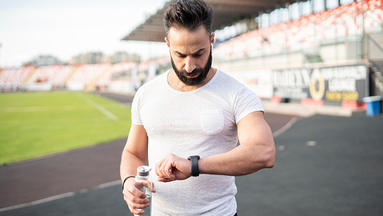 Adult man looking at his smart watch while doing sports outside