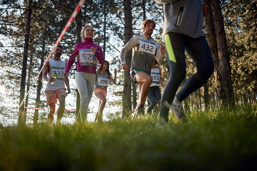 Group of amateur athletes running the race through the woods