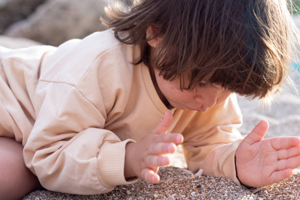 istock Little girl lying front and playing with sand on a beach at sunset. 1488901256
