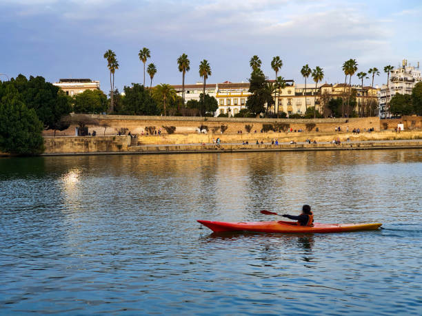 Seville, February 15, 2023. River Guadalquivir at sunset. In the background, the historic center of the city, seen from the bridge of Triana, or Isabel II. We see a kayak passing by.