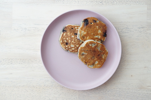 Healthy blueberry pancakes on a pink plate and wooden background table