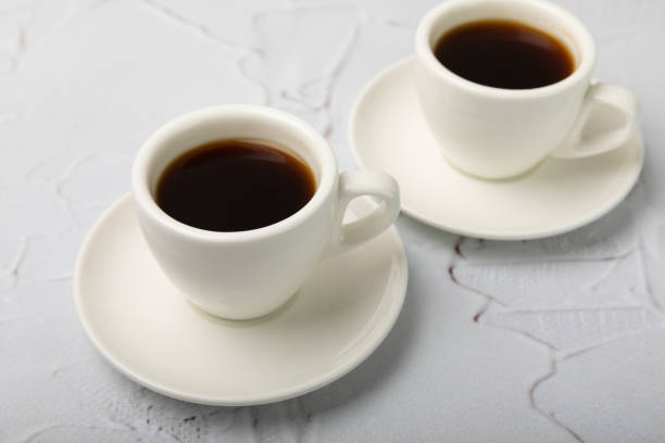 istock Hot coffee in a white coffee cup on a white texture table in a light atmosphere.Hot warming drink concept.Copy space.Side view.Place for text. 1488908495